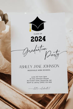 a graduation party card with a cap on it in a wooden box next to flowers