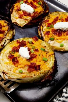 four baked potatoes with bacon and cheese on a baking sheet, ready to be cooked