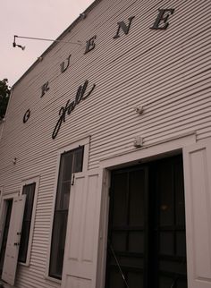 the side of a white building with black writing on it's windows and doors