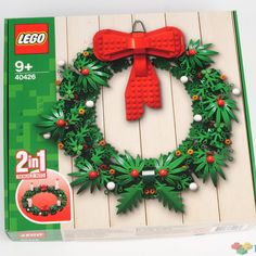 a christmas wreath made out of legos on top of a wooden wall next to a box