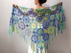 a woman wearing a blue and green crochet shawl with flowers on it