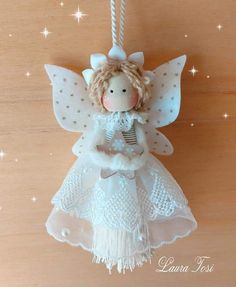 a white angel ornament hanging from a string on a wooden surface with stars in the background