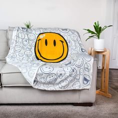 a couch with a smiley face on it and a potted plant in the corner