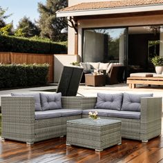 an outdoor living room with furniture on the wooden flooring and patio area in the background