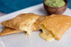 two pieces of food on a plate next to a bowl with guacamole