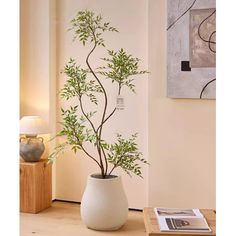 a potted plant sitting on top of a wooden table next to a painting and lamp