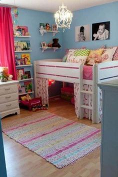 a child's bedroom with blue walls and white bunk beds, pink curtains, and colorful rugs