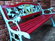 a red and white bench sitting next to a brick wall