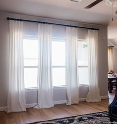 a living room filled with furniture and white curtains