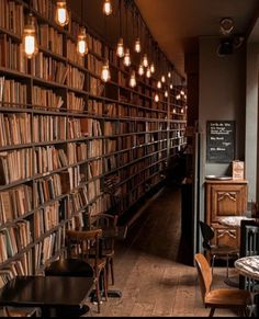 a long row of bookshelves filled with lots of books next to tables and chairs