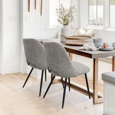 two grey chairs sitting on top of a wooden table in front of a white wall