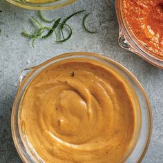 two bowls filled with sauce sitting next to each other on top of a gray surface