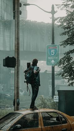 a man standing on top of a car in front of a street sign that reads 5 south