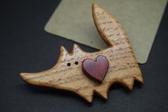 a wooden brooch with a red heart in the shape of a dog's head