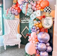 balloons are hanging on the wall in front of a white chair and checkerboard backdrop