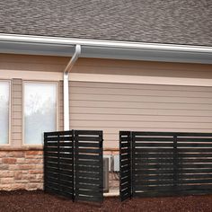 two black gates are in front of a house with a brick wall and brown siding