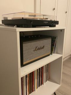 a record player sitting on top of a shelf filled with cds and cassettes in a room