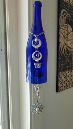 a blue glass bottle hanging from the side of a wall next to a painting and window