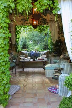 an outdoor living area with couches, chairs and tables covered in green ivy leaves