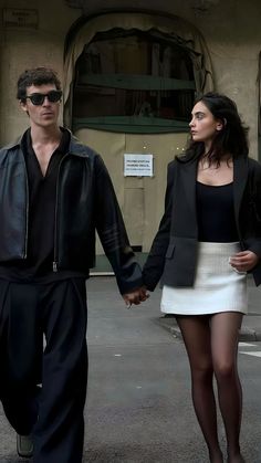 a man and woman walking down the street holding hands