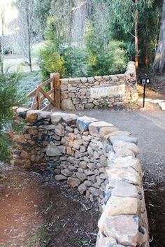 a stone wall and wooden gate in the woods