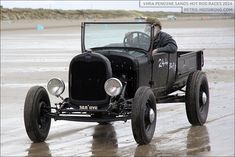 an old fashioned car driving on the beach