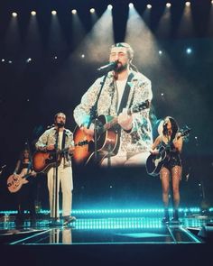 a group of people that are on stage with guitars