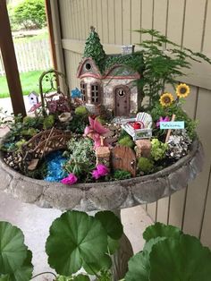 a potted planter filled with lots of flowers and small houses on top of it