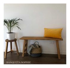 a wooden bench sitting next to a potted plant on top of a hard wood floor