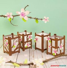 three wooden boxes with flowers painted on them sitting on a table next to a branch