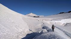 people hiking up the side of a snow covered mountain