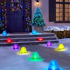 colorful lights on the ground in front of a house with christmas trees and wreaths