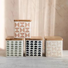 three ceramic containers with geometric designs on them