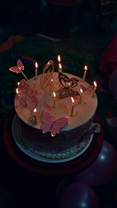 a birthday cake with candles and butterflies on it