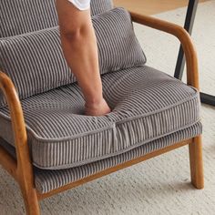 a person standing on top of a chair with their foot in the armrests