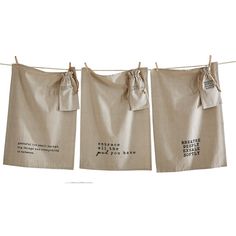 three tea towels hanging on a clothes line with words written in black and white ink