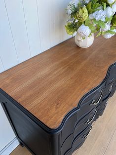 a black and brown dresser with flowers on top