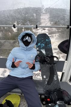 a man sitting on top of a ski lift holding his hands up in the air