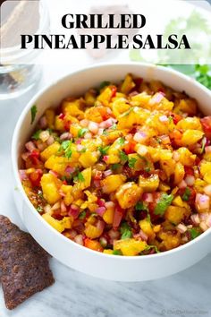 a white bowl filled with salsa next to tortilla chips and cilantro