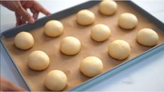 a pan filled with doughnuts sitting on top of a counter next to a person's hand