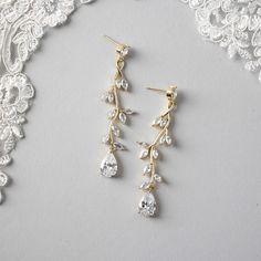 two pairs of gold earrings with crystal drops hanging from the end of each earring