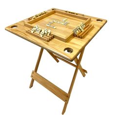 a wooden tray with dominos on it sitting on top of a folding table legs