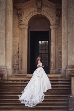 a woman in a wedding dress standing on the steps of an old building with stairs