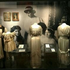 an old fashion display with mannequins, dresses and pictures on the wall