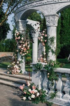 an arch covered in flowers and greenery next to steps