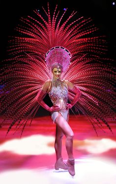 a woman is walking down the runway in a costume with feathers on it's head