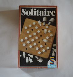 a wooden board game with white pieces on it and the words solitaire written in black