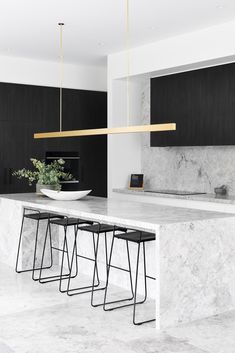 a modern kitchen with marble countertops and black cabinetry, along with bar stools