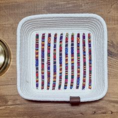 a close up of a pot holder on a wooden surface with a metal object in the background