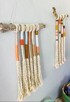 two wall hangings made out of rope and wood sticks with different colors on them